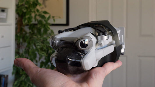 a DJI Mini 5 pro folded up in the palm of someones hand in a bedroom environment