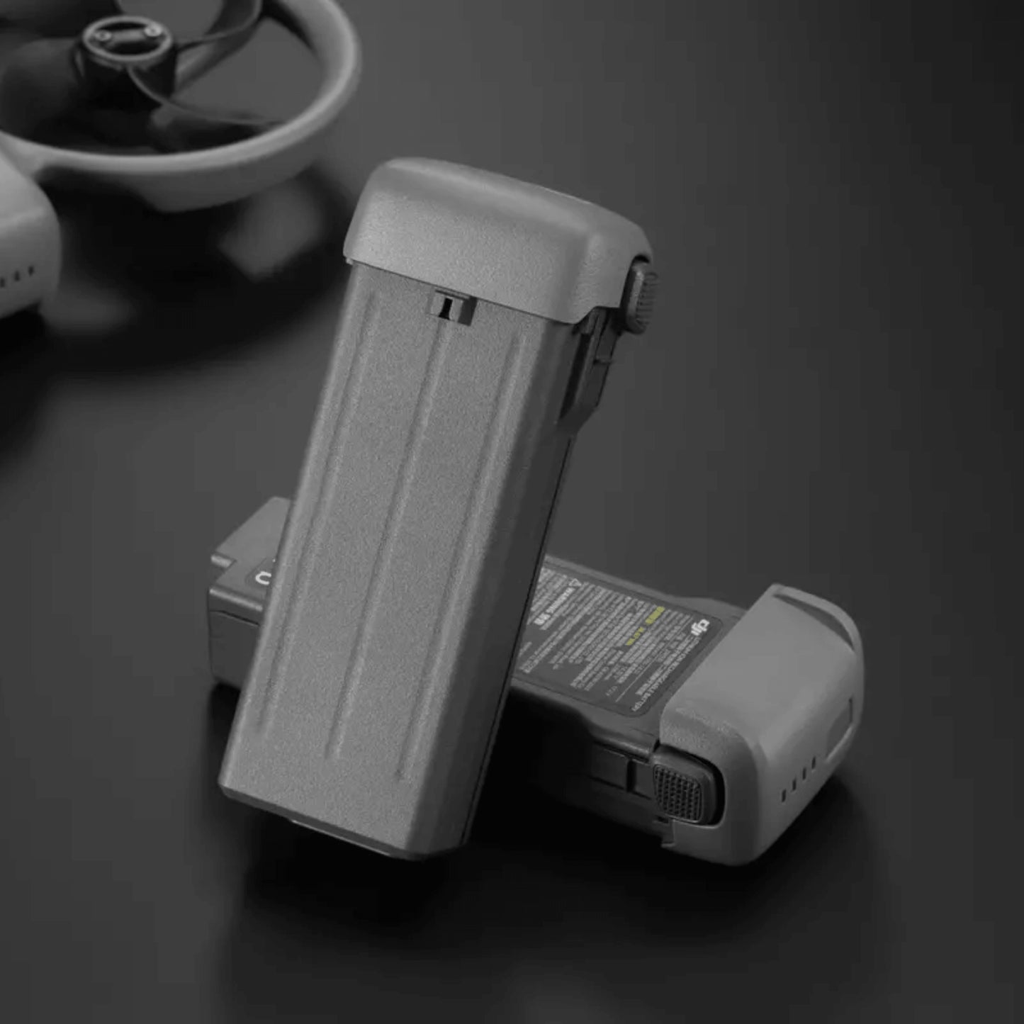 Two DJI Avata 360 intelligent flight batteries on a dark surface with a blurred background