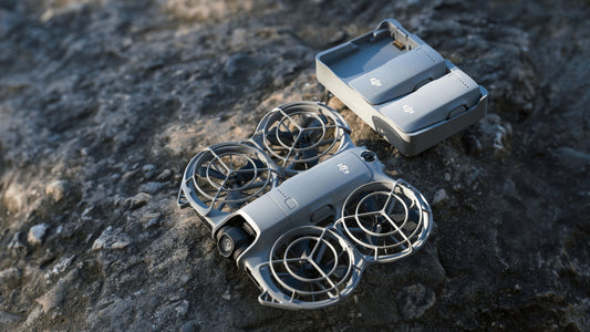 dji neo 2 drone next to the charging-hub with 2 batteries charging on a rocky base