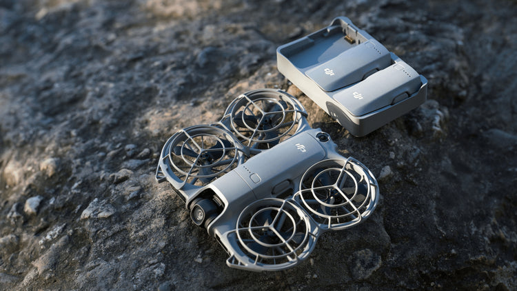 dji neo 2 drone next to the charging-hub with 2 batteries charging on a rocky base