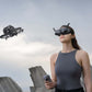 Woman wearing DJI goggles integra controlling a dji avata drone with a dji rc motion 3 against an urban skyline.
