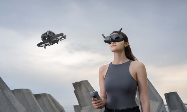 Woman wearing DJI goggles integra controlling a dji avata drone with a dji rc motion 3 against an urban skyline.